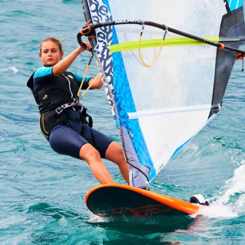 Torbole - Nago, Lago di Garda (Lago Benaco), Italy - July 18, 2019: A windsurfing on Lake Garda in Torbole resort. Windsurfer Surfing The Wind On Waves, Recreational Water Sports, Selective focus
